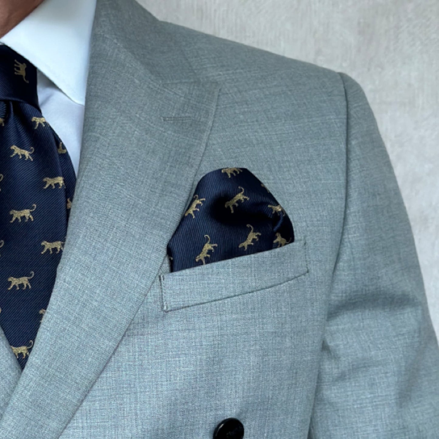 Torso of a model wearing a grey double breast blazer with a leopard print pocket square