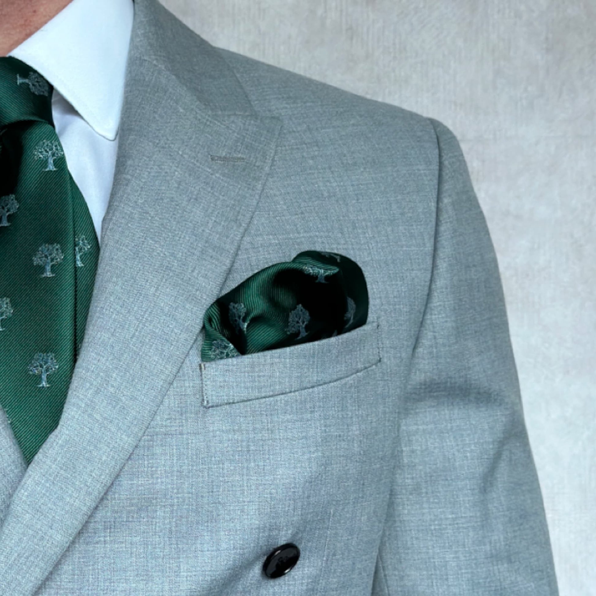 Torso of a model showcasing a green and silver tree embroidered pocket square