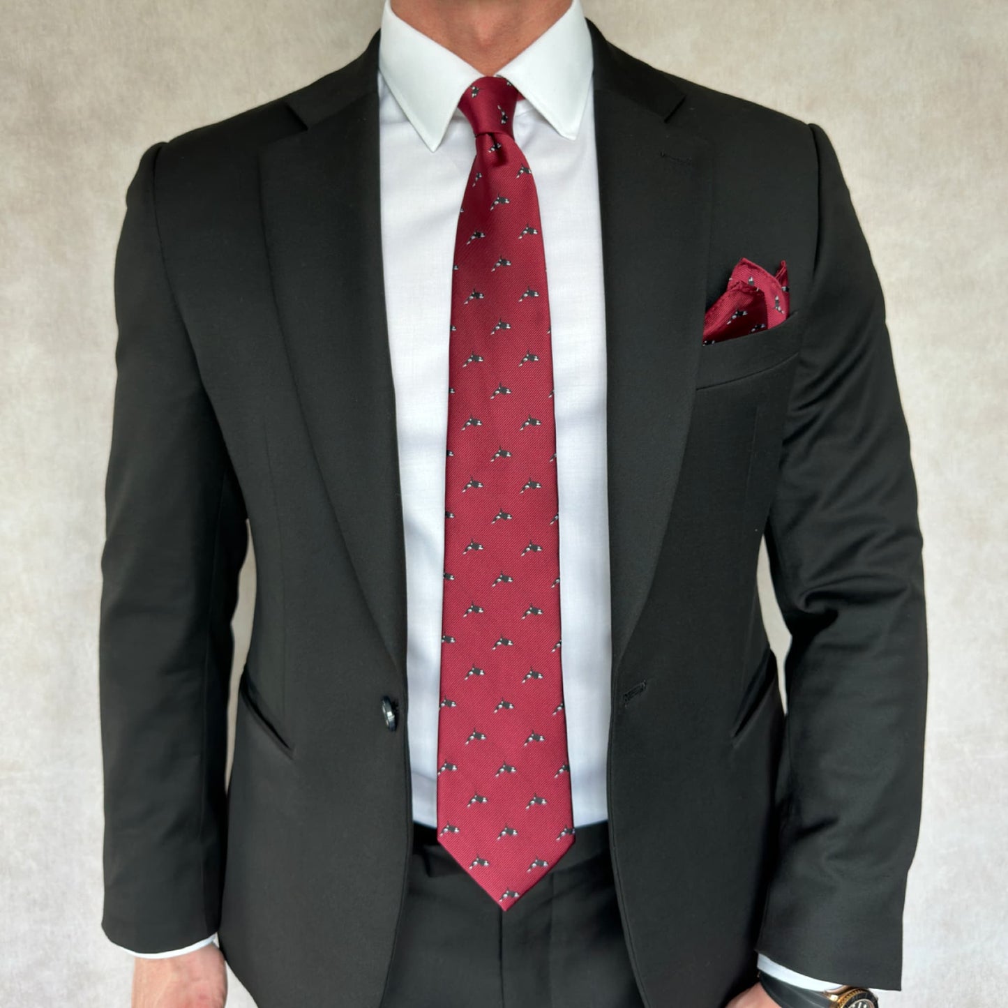 model wearing black suit and white shirt displaying red tie and pocket square printed with killer whale motif