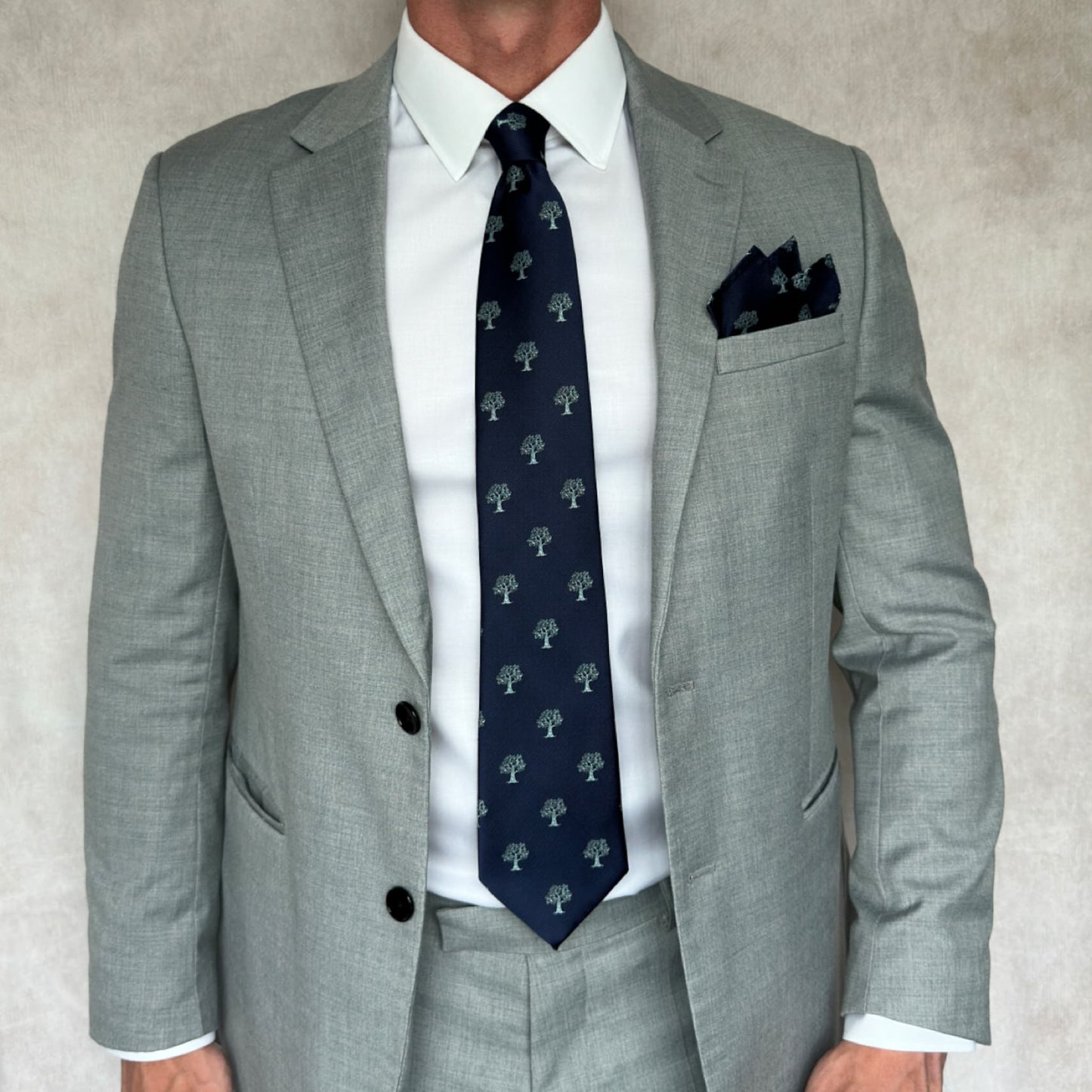 Model in grey suit and white shirt displaying blue and silver tree pattern tie