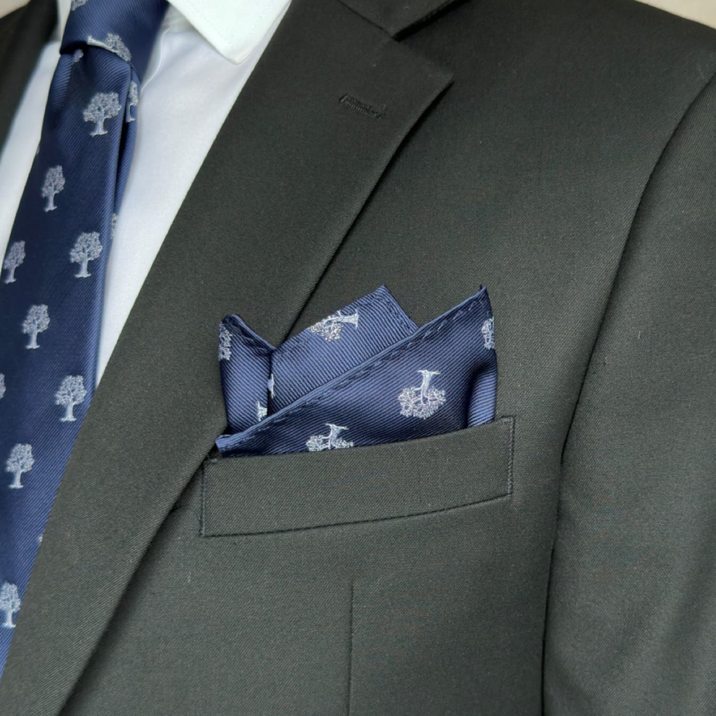 black suit pocket displaying blue pocket square accented white tree pattern