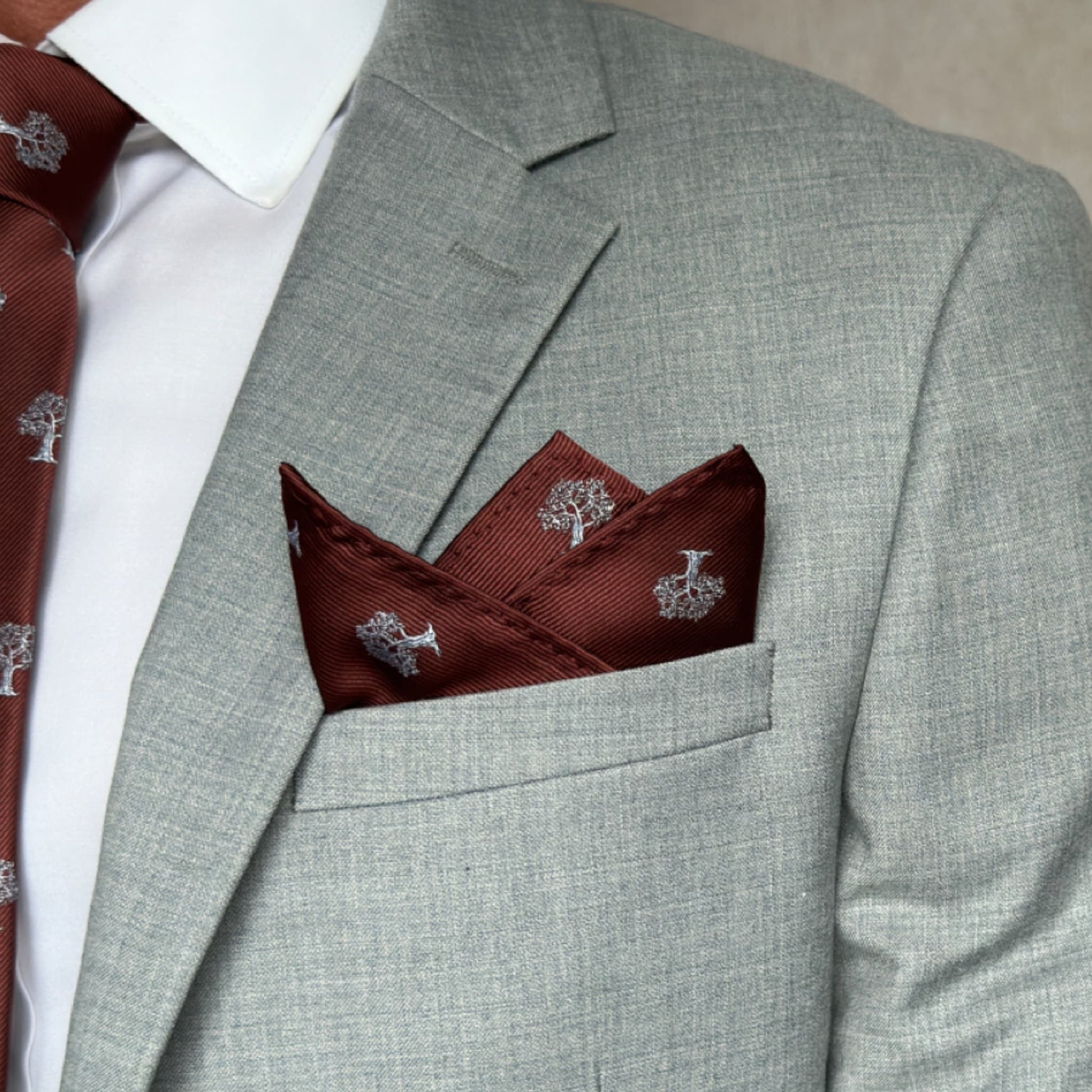 model showcasing a neatly folded brown pocket square with white tree pattern