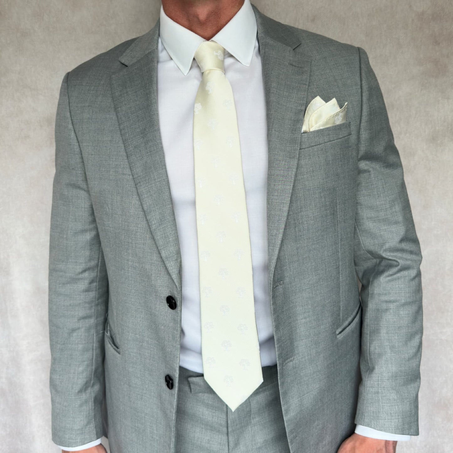 model wearing grey open suit and white shirt with ivory and white tree embroidered necktie and pocket square set