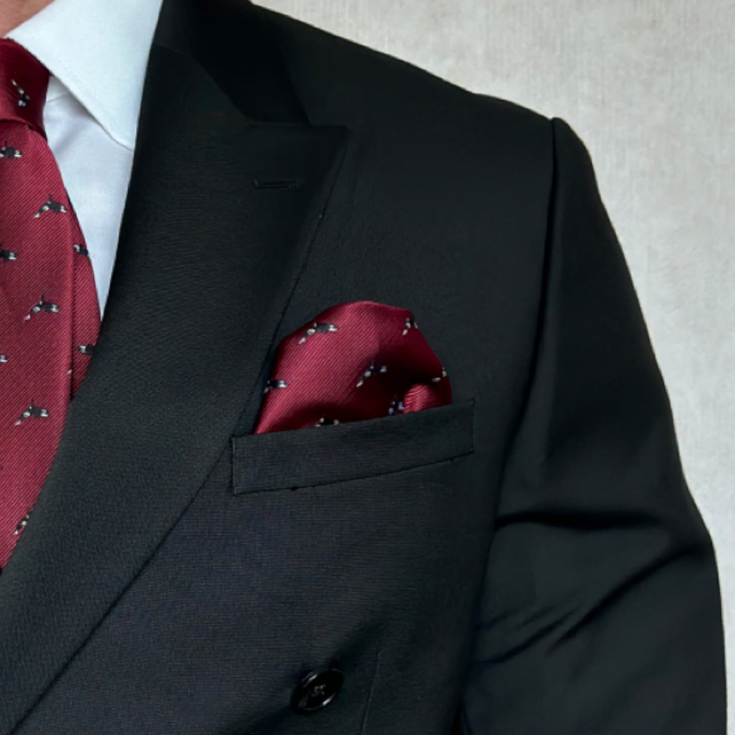 Black suit pocket highlighting red orca patterned pocket square 