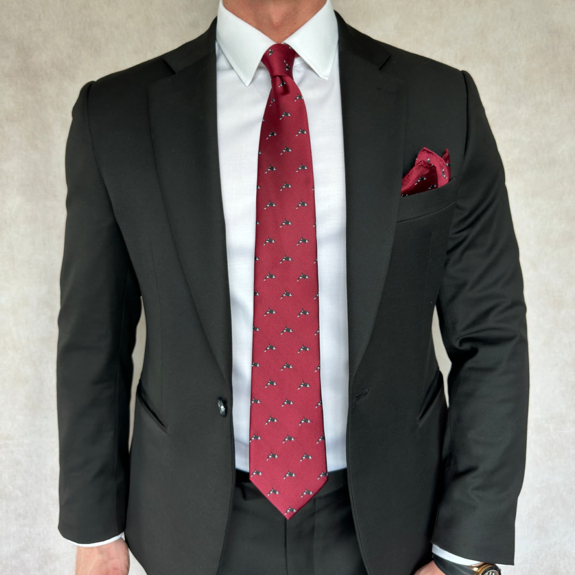 model wearing black suit and white shirt displaying red tie and pocket square printed with killer whale motif 