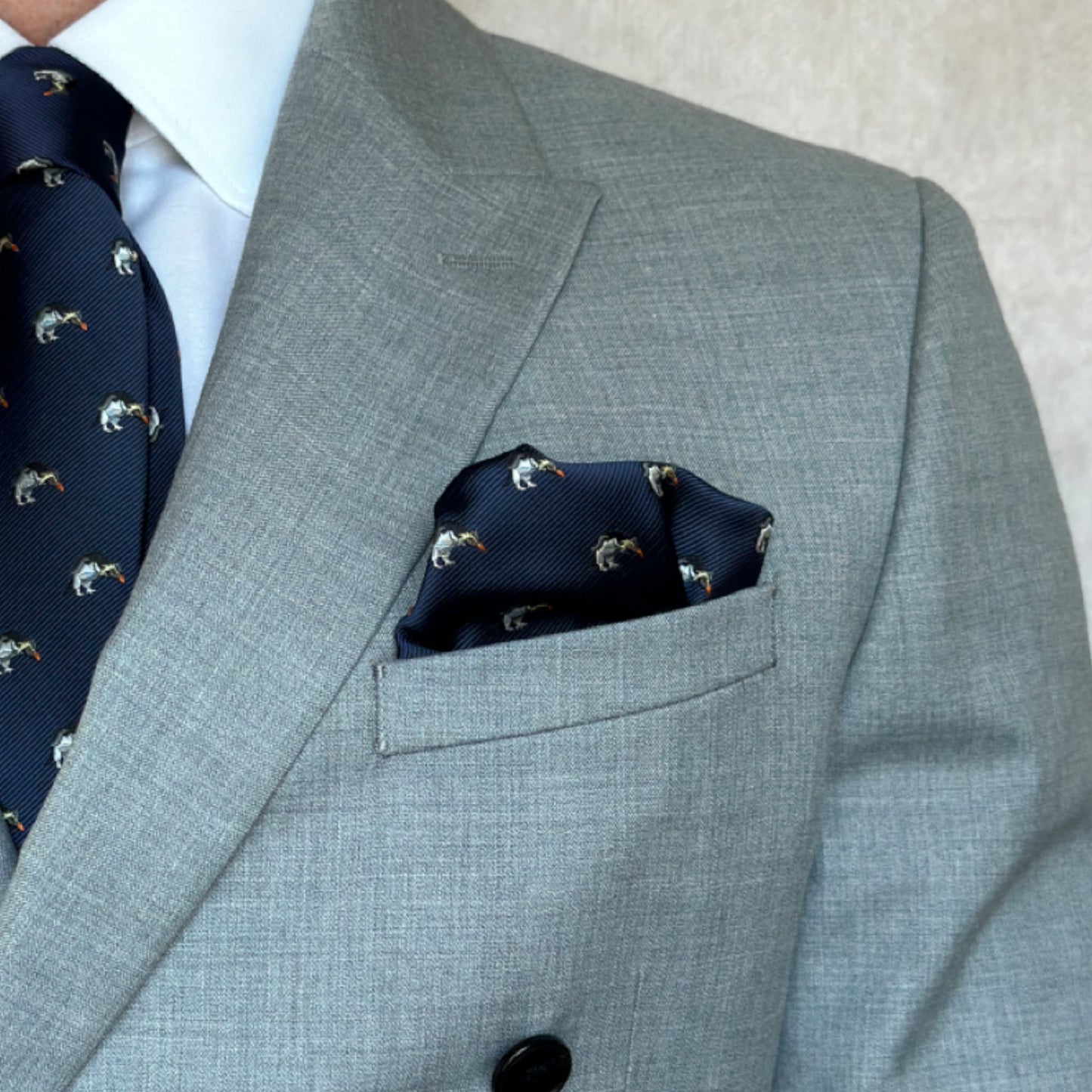 grey suit showcasing navy blue animal style penguin pocket square