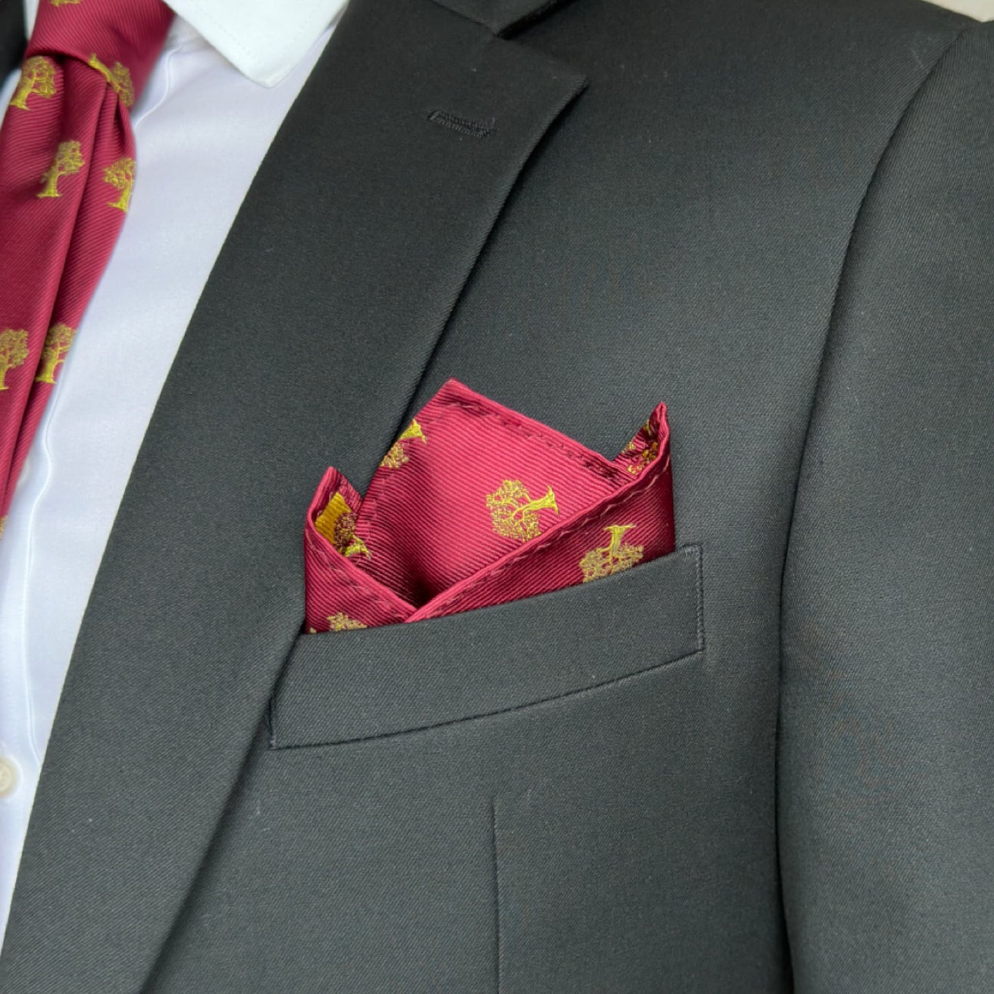 Black suit pocket displaying stunning red and gold tree pocket square 