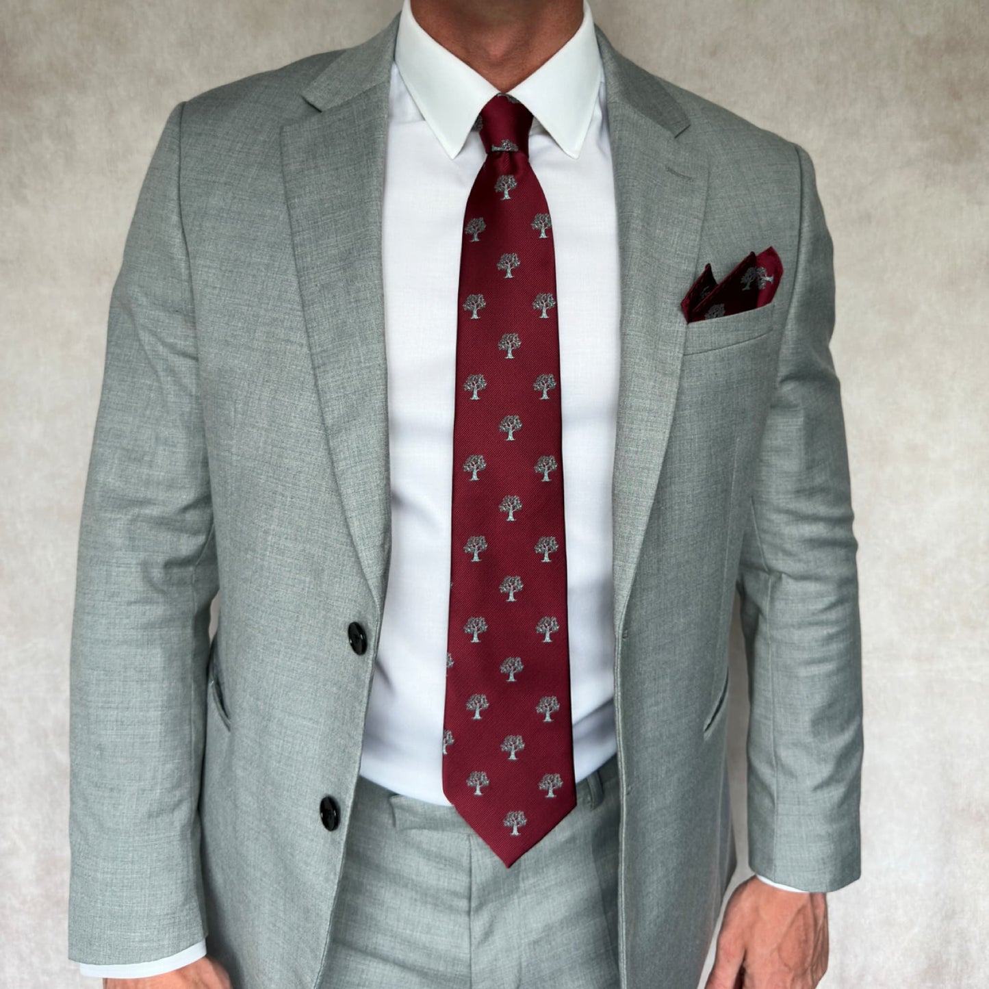 Model wearing grey suit showcasing matching red and silver tie and pocket square set