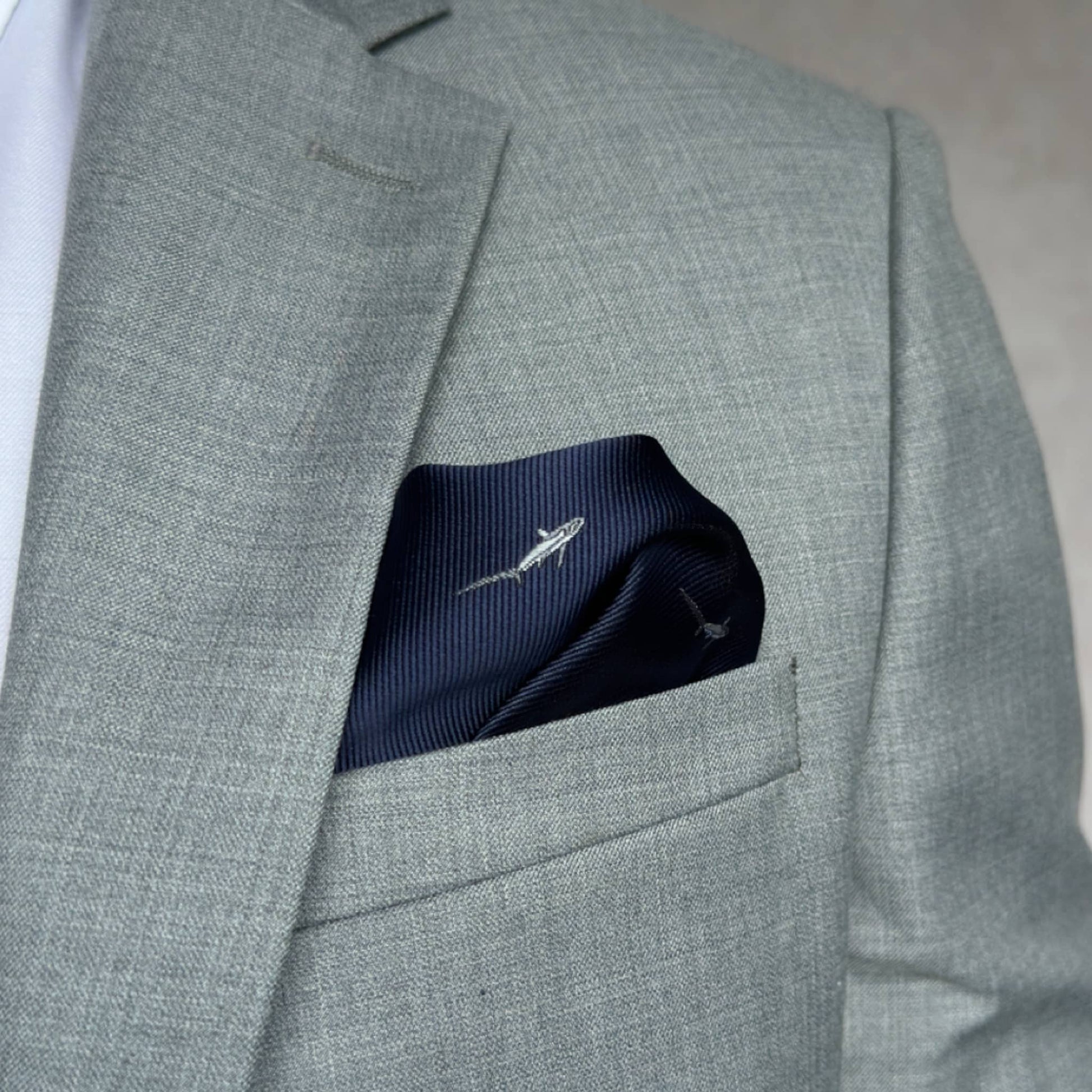 grey suit pocket embracing a blue pocket square with thresher shark embroidery