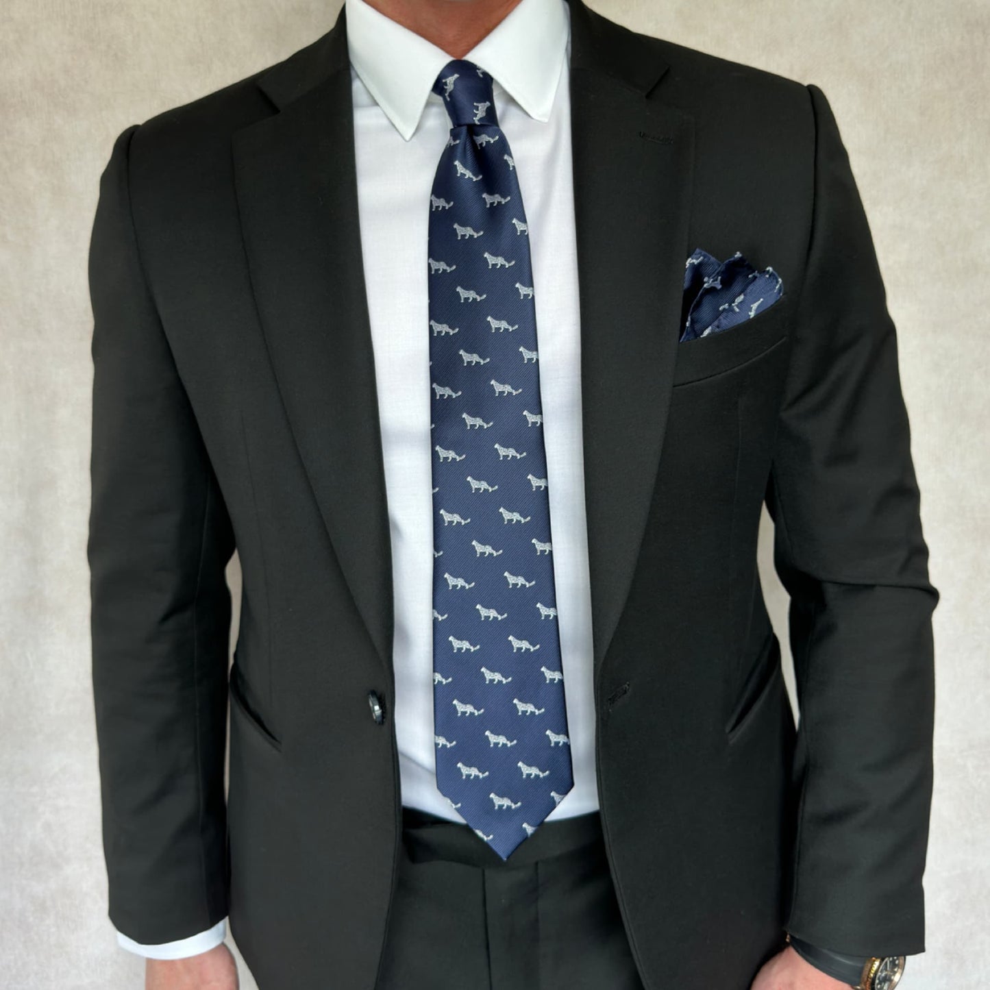 Model showcasing black suit along with blue and white snow leopard necktie