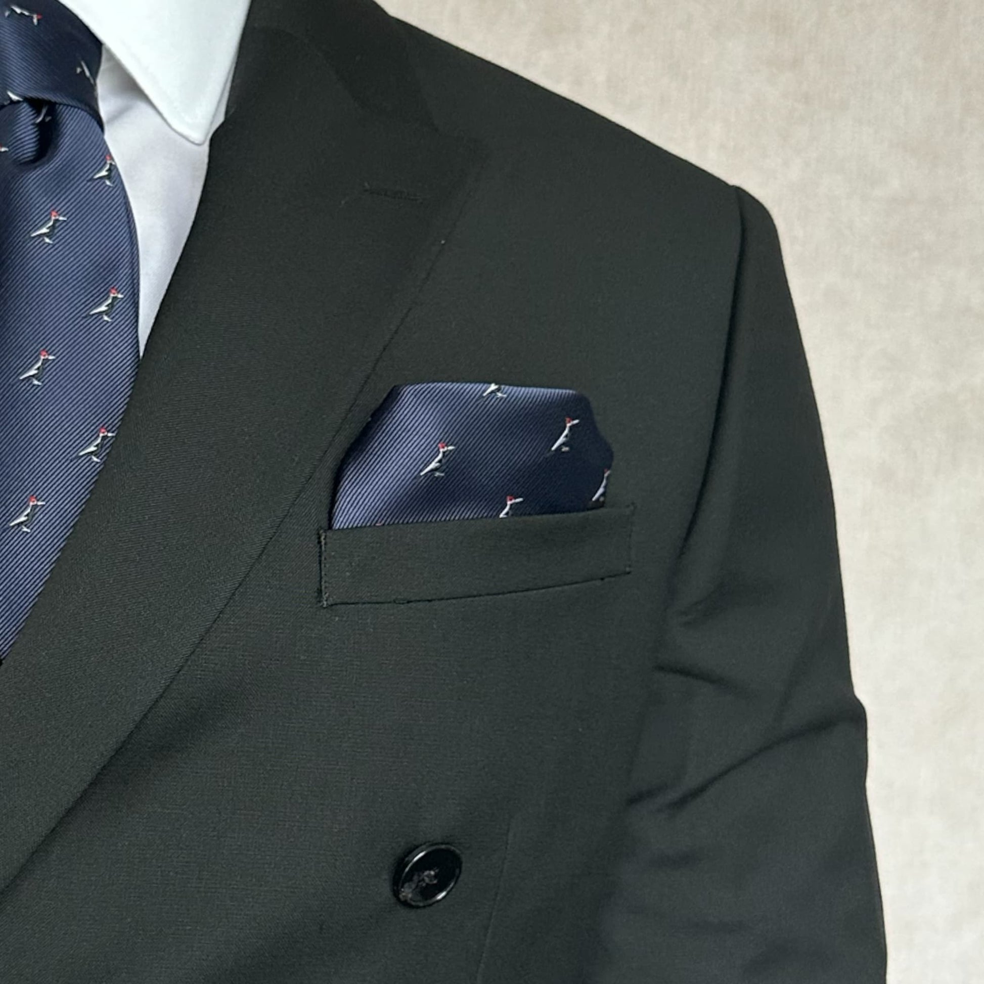 black blazer displaying blue pocket square with bird stitching