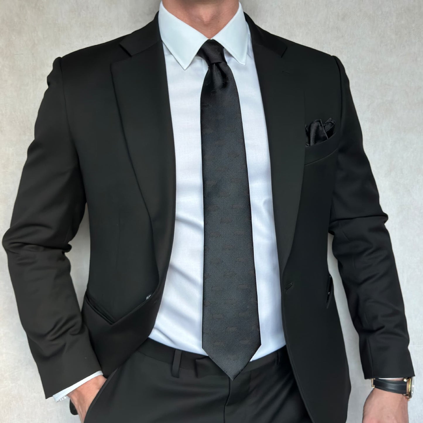 Model wearing an open black suit and white shirt along with a blackout tie that has a rhino pattern